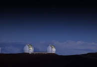 The two Keck telescopes peering out into the night sky, while darkness falls upon them. The summir of Mauna Kea sits so high that the clouds are almost always beneath the Keck telescopes. - Rick Peterson